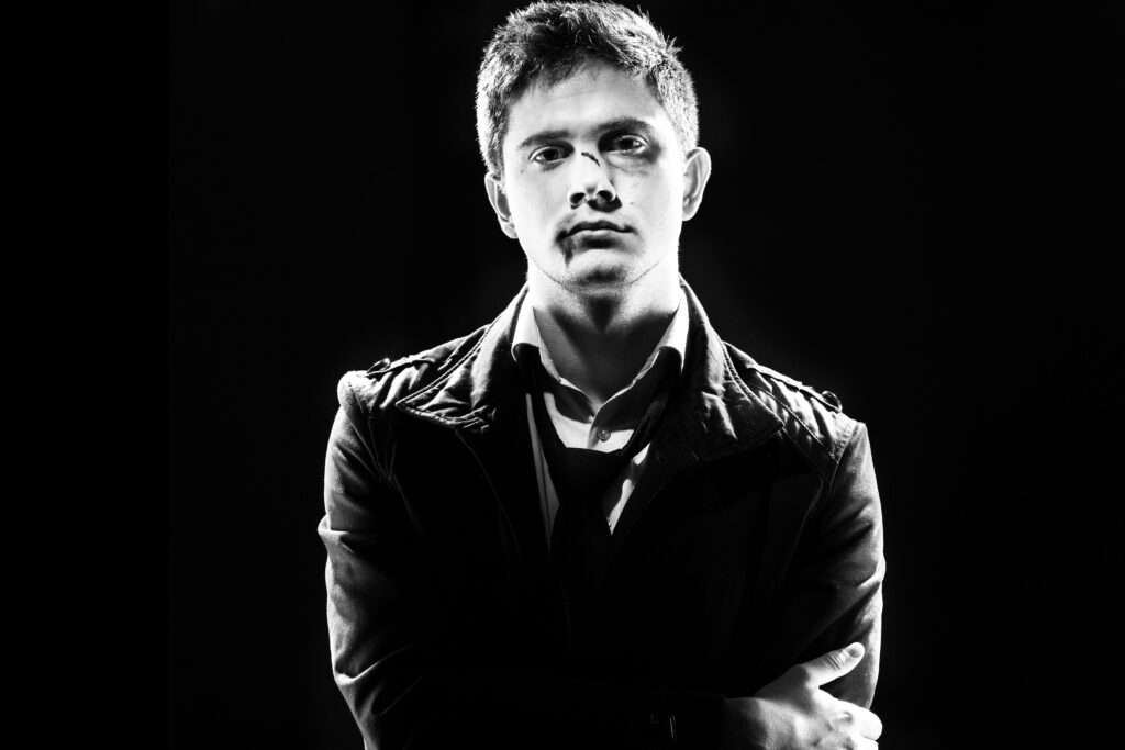 portrait young man standing against black background